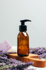 Set of natural cosmetics. Amber bottles with facial, bath liquid on a concrete background with lavender flowers. Front view