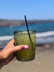 Refreshing Green Drink Held by the Beach with Ocean View