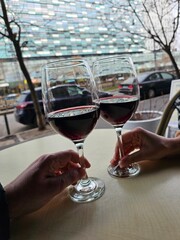 Two friends enjoying a glass of red wine at an outdoor cafe. The relaxed atmosphere and urban setting make this image perfect for capturing the essence of casual dining and socializing.