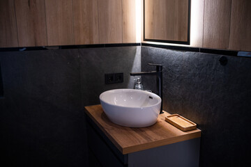 Modern bathroom sink design with a sleek white basin and wooden countertop under warm lighting