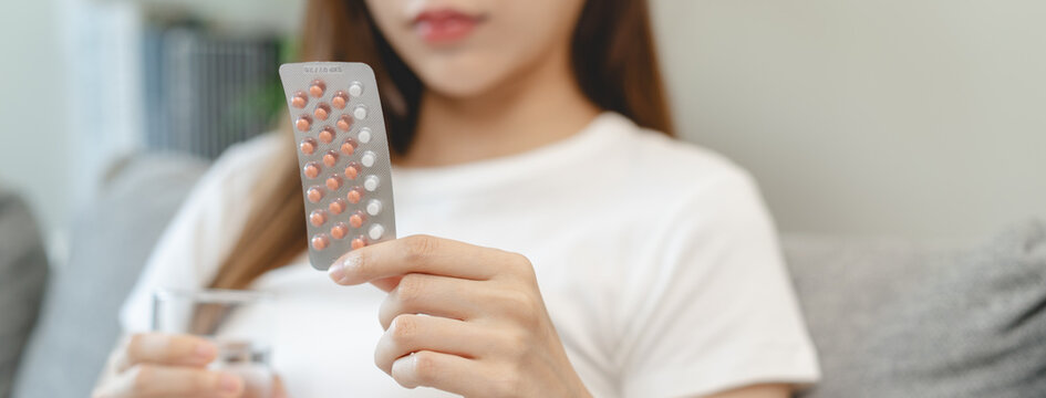 young female holding birth control pills