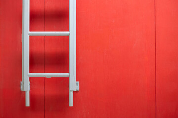 A ladder leaning against a red wall