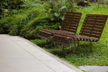 A pair of wooden park benches sit on a grassy hillside