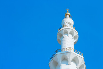 A mosque minaret against clear blue sky with copy space on left side