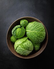 Fototapeta premium green cabbage in a bowl on a black background, top view, copy space 