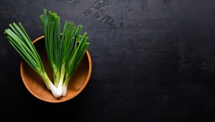 Green onion in a bowl on a black background, top view, copy space 