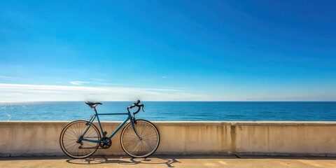 Fototapeta premium Road bicycle parked against a wall by the seaside with a clear blue sky backdrop, road bicycle, wall, seaside