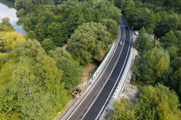
A new modern automobile bridge over the river on the background of the blue sky. A sturdy reinforced concrete bridge, thick concrete pillars and metal floors.
