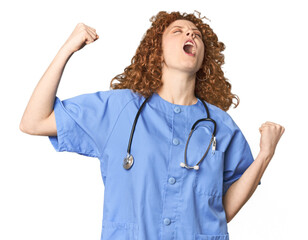 Young Caucasian redhead woman as nurse raising fist after a victory, winner concept.