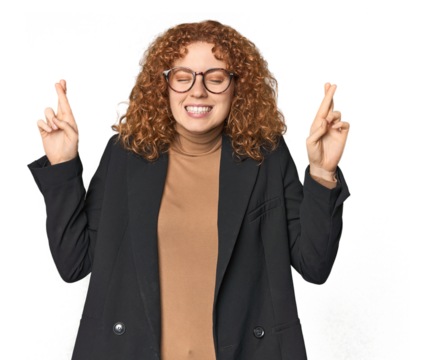 Young Caucasian redhead in business attire crossing fingers for having luck