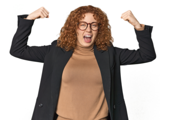 Young Caucasian redhead in business attire showing strength gesture with arms, symbol of feminine power