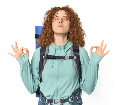 Young Caucasian redhead ready for hiking relaxes after hard working day, she is performing yoga.