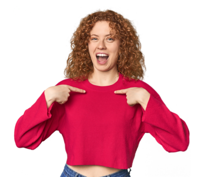 Young Caucasian redhead woman surprised pointing with finger, smiling broadly.