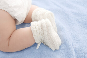 baby feet in warm woolen white stockings on a blue blanket 