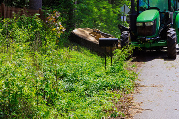 Grass branches have been cut on both sides of road with municipal service tractor equipped with mower