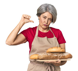 Caucasian mid-age baker with bread loaves feels proud and self confident, example to follow.