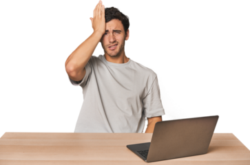 Hispanic young man working on laptop forgetting something, slapping forehead with palm and closing eyes.