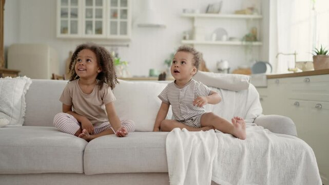 Two happy black kids playing with balloons in apartment, joyful little children. Happiness and joy, emotional African American girlie hitting balloon up and smiling, toddlers siblings, happy childhood