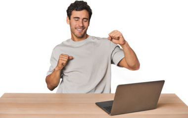 Hispanic young man working on laptop dancing and having fun.