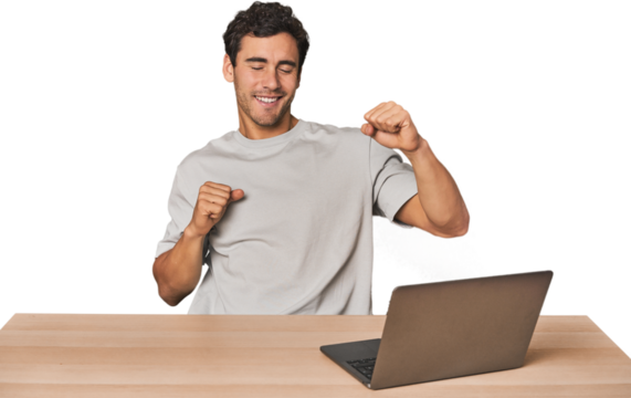 Hispanic young man working on laptop dancing and having fun.