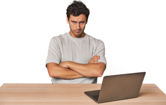 Hispanic young man working on laptop unhappy looking in camera with sarcastic expression.