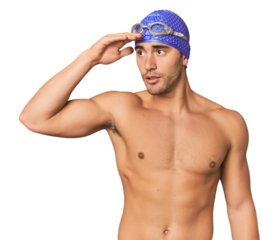Young Hispanic man with swim gear looking far away keeping hand on forehead.