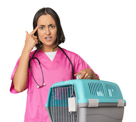 Young Caucasian female vet holding cage showing a disappointment gesture with forefinger.