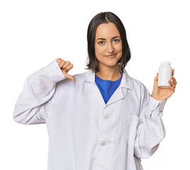 Young Caucasian female pharmacist with pills showing a dislike gesture, thumbs down. Disagreement concept.