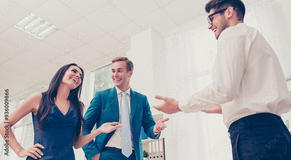 Wall mural Portrait of three happy colleagues discussing new task and smiling