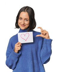 Young Caucasian woman with heart sign in studio