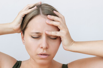 Fototapeta premium Young caucasian blonde woman feeling dizzy holding her head with hand on light background. Dizziness, vertigo, fatigue, low blood pressure, anemia, headache, migraine, exhaustion, emotional breakdown