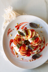 bagel with cream cheese, peaches and blueberries on a white plate on a light table