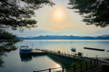 Sunset on the lake with boats and mountains in the background