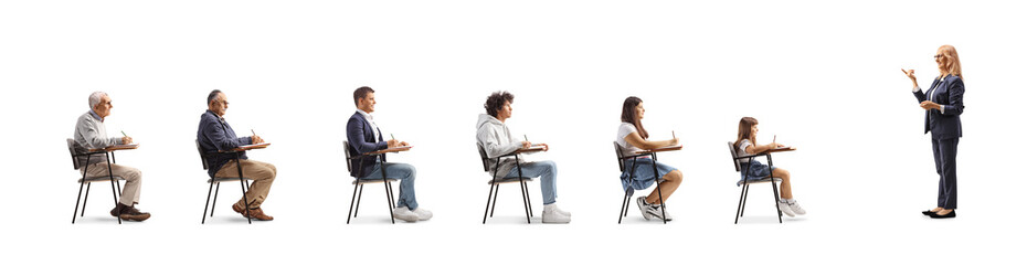 Woman talking to people seated in school chairs in a row
