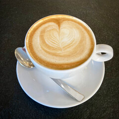 Cappuccino, cup top view, original Italian cappuccino with cream, latte foam art coffee with heart dark background 