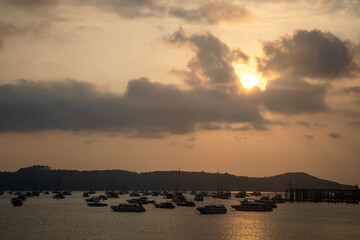 Yachts are moored in the bay. Sunny morning. Sky with clouds. Silhouettes of yachts on the water.