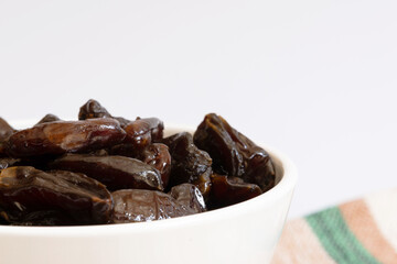 Portion of dates inside a white bowl photographed close up