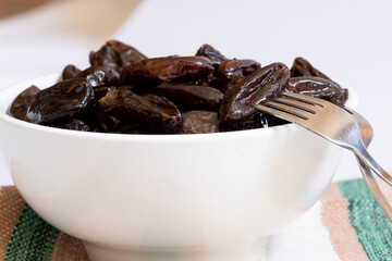 Portion of dried dates inside a white ceramic bowl photographed close up