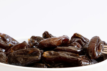 Portion of dried dates inside a ceramic bowl photographed close up