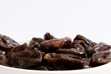 Portion of dried dates in a white bowl photographed close up