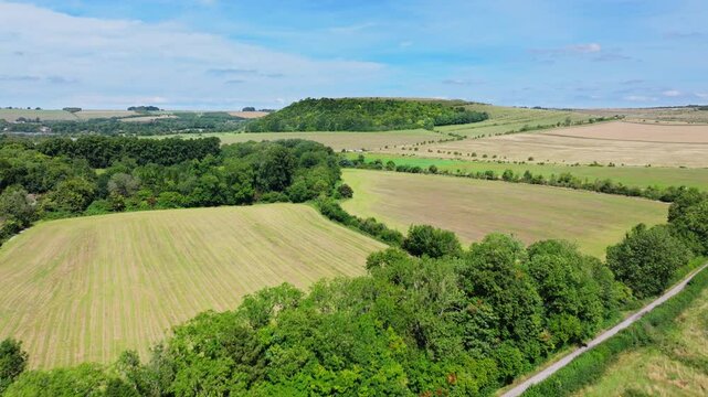 Aerial shot flying over the Wiltshire countryside towards an iron age Battlebury hill fort in the distance