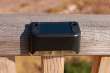 Small solar powered led light with motion sensor on wooden terrace