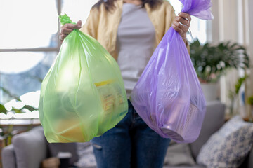 woman is holding bag for sorting garbage.  Trash can for Waste sorting in home. Female take out trash. Volunteer save earth protection.