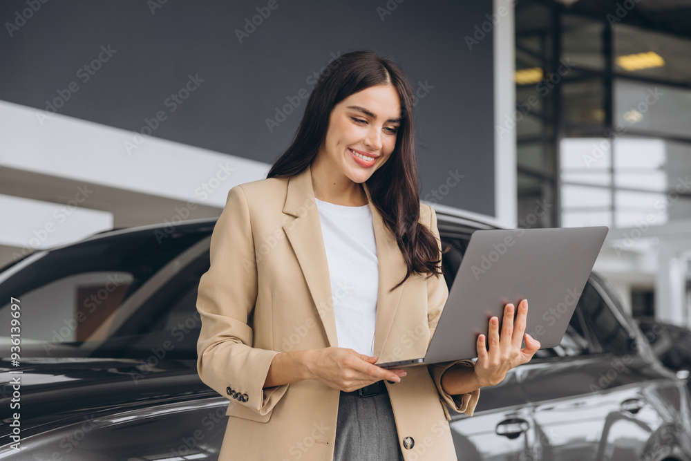 Wall mural portrait of confident successful sales woman using laptop computer standing near new car in car deal