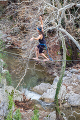 A tightrope walker walks along a cable stretched over a canyon.