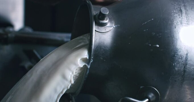 Super slow motion macro of artisan cheesemaker is adding fresh bio eco milk during traditional cheese making process at cheese production creamery dairy factory at 1000 fps.
