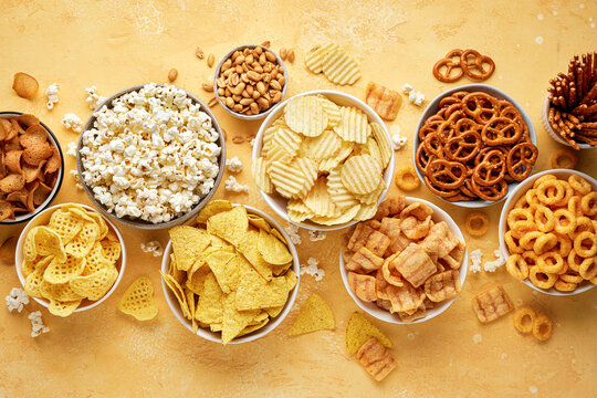 Set of many bowl with different salty snacks. Chips, popcorn, nuts, nachos and pretzels