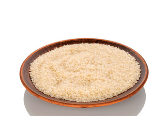 Round grain uncooked rice in a clay plate, macro, isolated on white background..