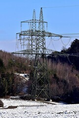Eine imposante 380-kv-Leitung durch den Wald und auf dem Boden liegt etwas Schnee