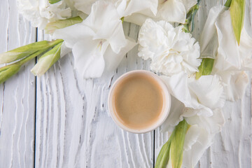 Beautiful bouquet of white carnations and gladioli and coffee